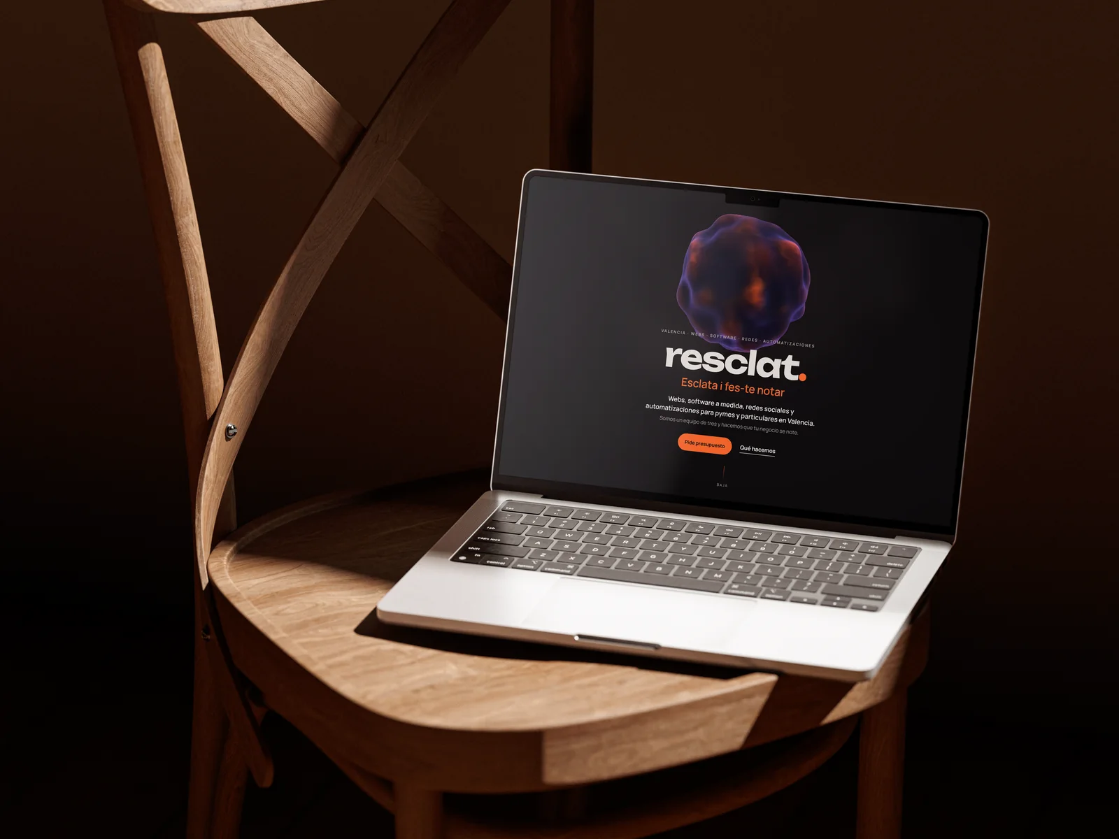 Portátil sobre una silla de madera mostrando la portada de la web de Resclat