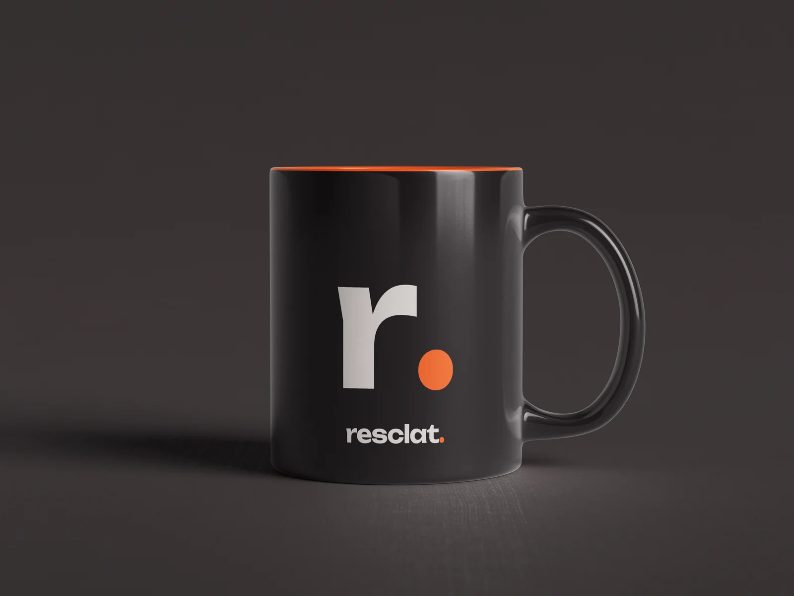 Taza negra de Resclat con la r. del isotipo y el interior naranja